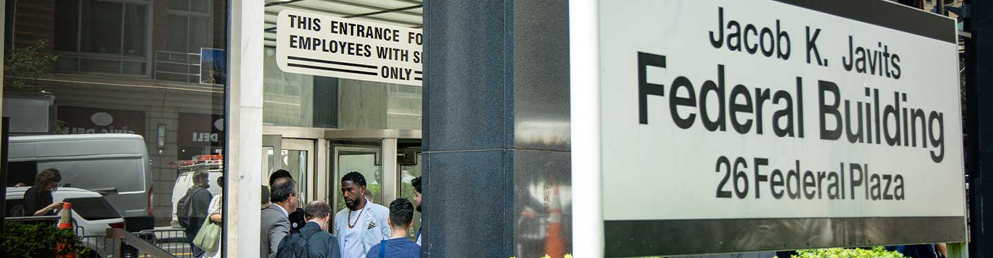 The Public Advocate speaks with the Comptroller and staff members. A sign outside the building reads: Jacob K. Javits Federal Building, 26 Federal Plaza