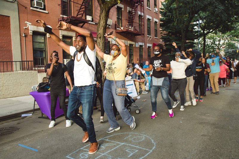 Public Advocate Williams raises his arms over his head, leading a line of happy dancers at National Night Out in 2021.