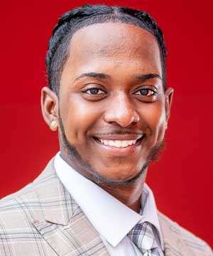  Jeff Senatus smiling with teeth outside with red background 