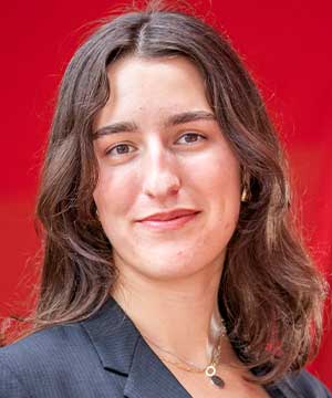 Headshot of Kate Marriott, a white woman with dark brown hair wearing a white tank top and a black blazer. Kate smiles directly at the camera.