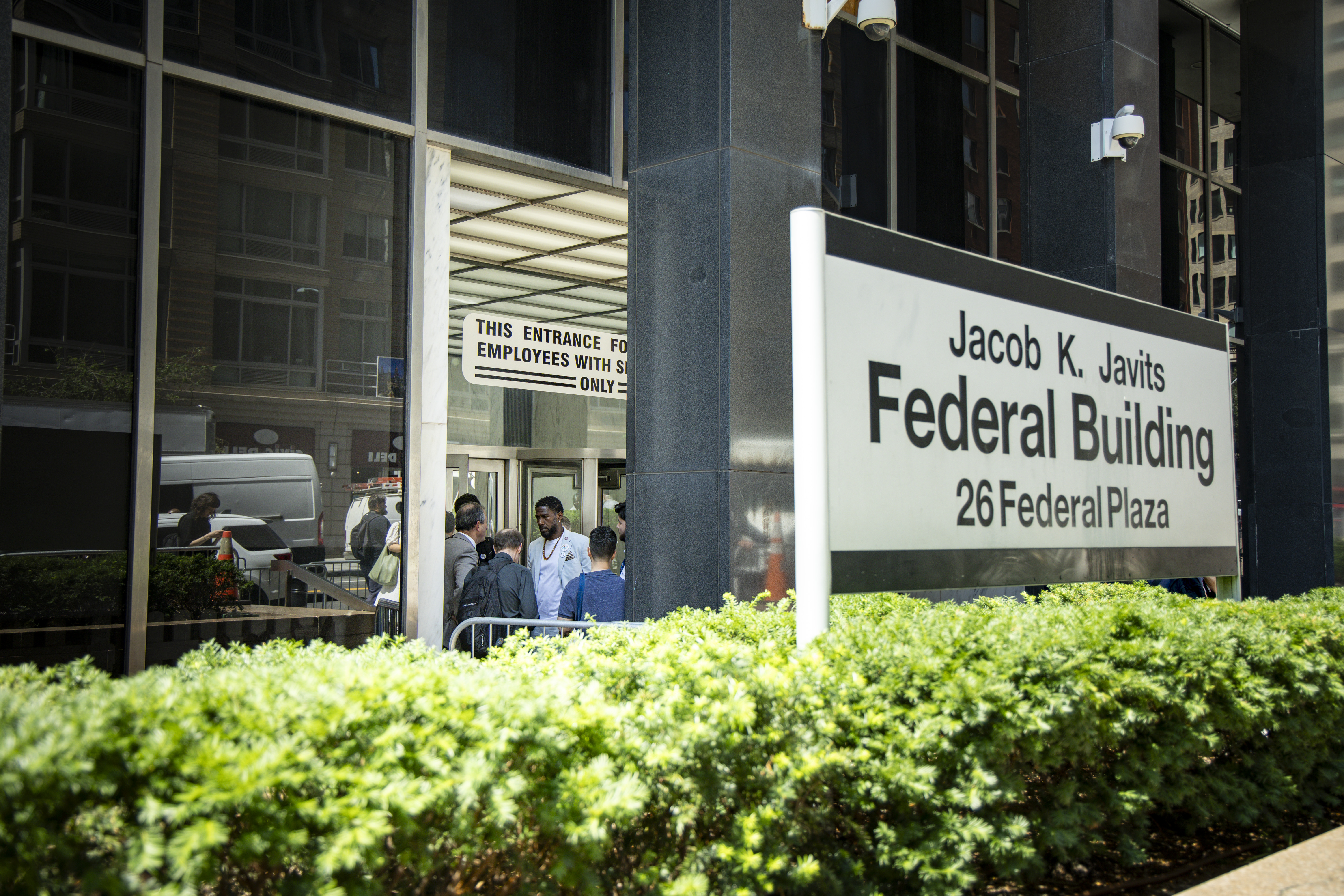 The Public Advocate speaks with the Comptroller and staff members. A sign outside the building reads: Jacob K. Javits Federal Building, 26 Federal Plaza