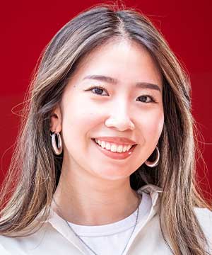 Headshot of Ana, an Asian woman with long brown hair and a white top smiling directly at the camera.