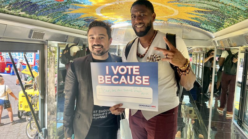 Public Advocate Williams poses with NYCCEC staffer in the People's Bus, holding an &quot;I Vote Because...&quot;Poster