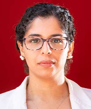 A brown woman with glasses looking directly at the camera.