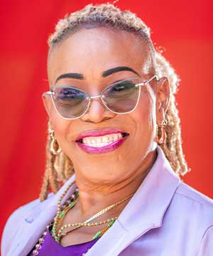 Headshot of Kim Watson-Benjamin, A Black Caribbean woman with Blonde braided hair. Kim is smiling.