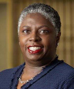 Headshot of Dynishal Smith, a Black woman with short, graying  hair. Smith smiles directly at the camera.