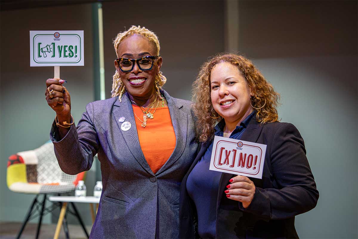 Team members smile as they hold up "Yes!" and "No!" signs